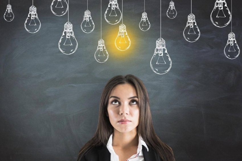 Young woman thinking about vocational training options in Ajman under a lit lightbulb